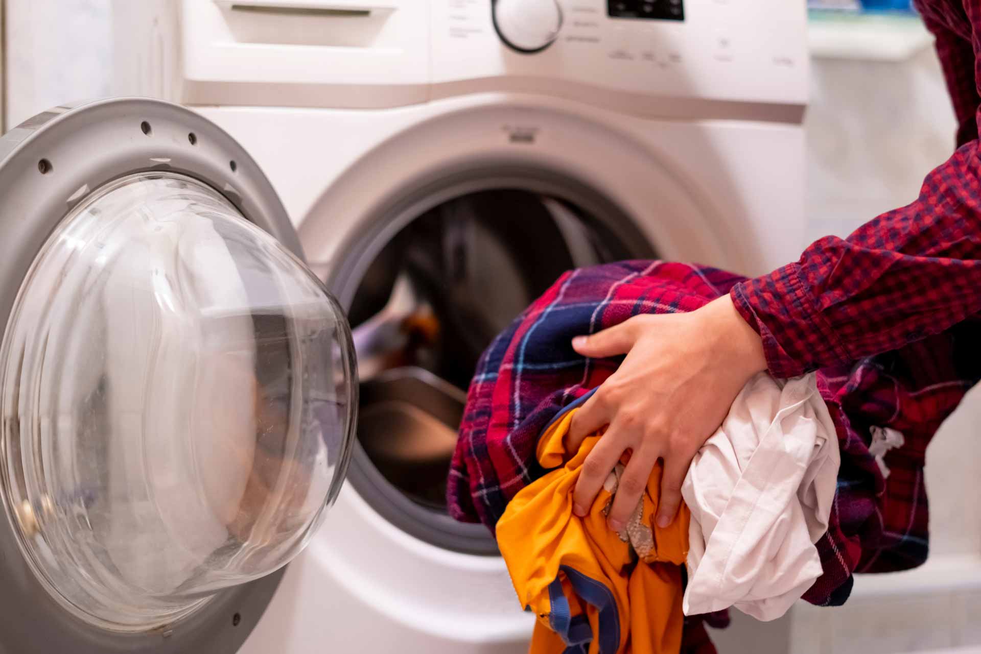 Homeowner standing with load of laundry in front of broken washing machine