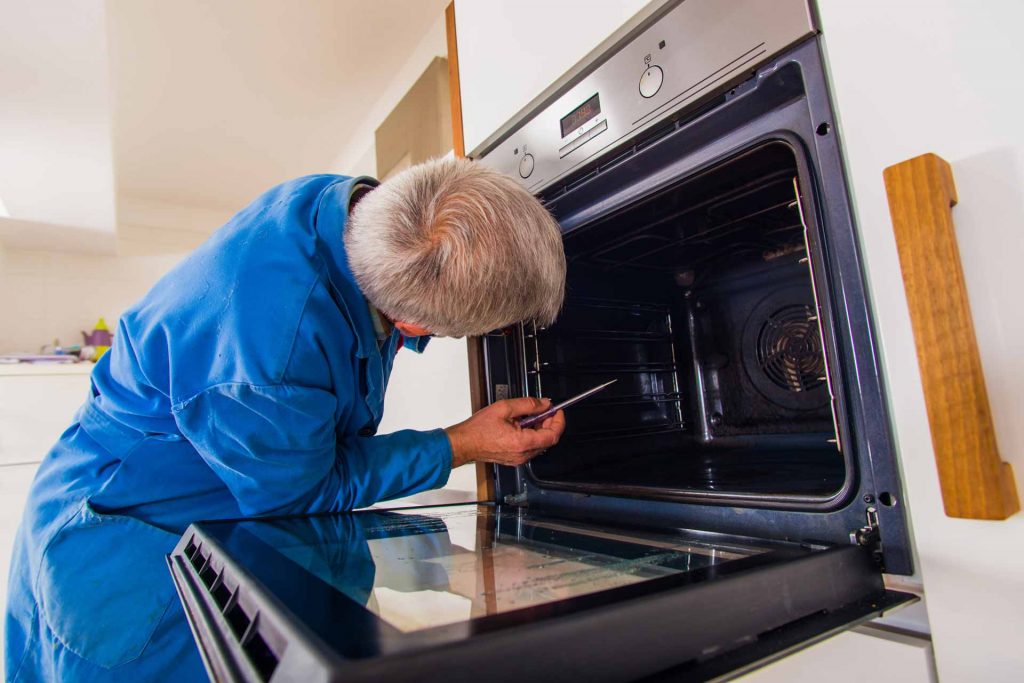 Oven repair technician working on a wall oven