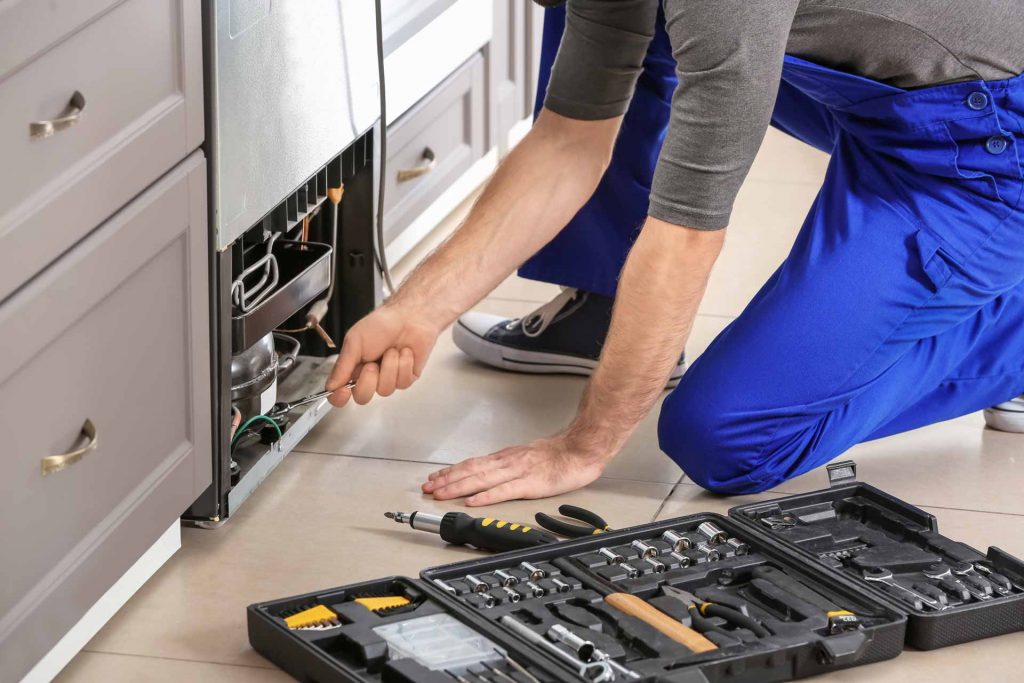 Appliance repair technician at work on a refrigerator